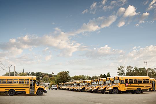 Large fleet of yellow school buses parked in a lot. 