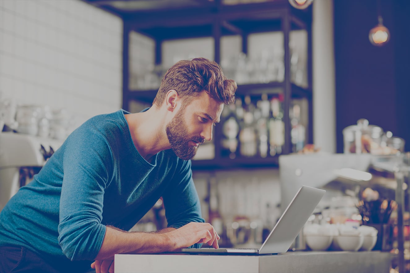 Man working with a laptop at the counter of a café