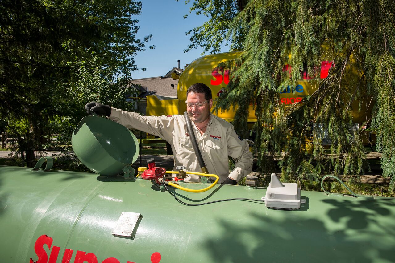 Superior Propane employee opening a green propane tank preparing to refill it. 