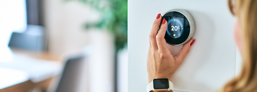 woman’s hand adjusting home thermostat