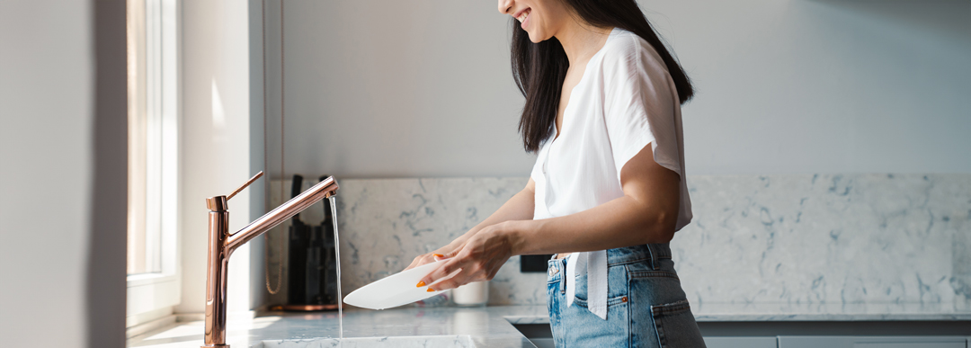 woman washing dishes with warm water