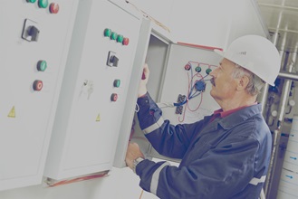 Construction worker making adjustments to an electrical panel. 