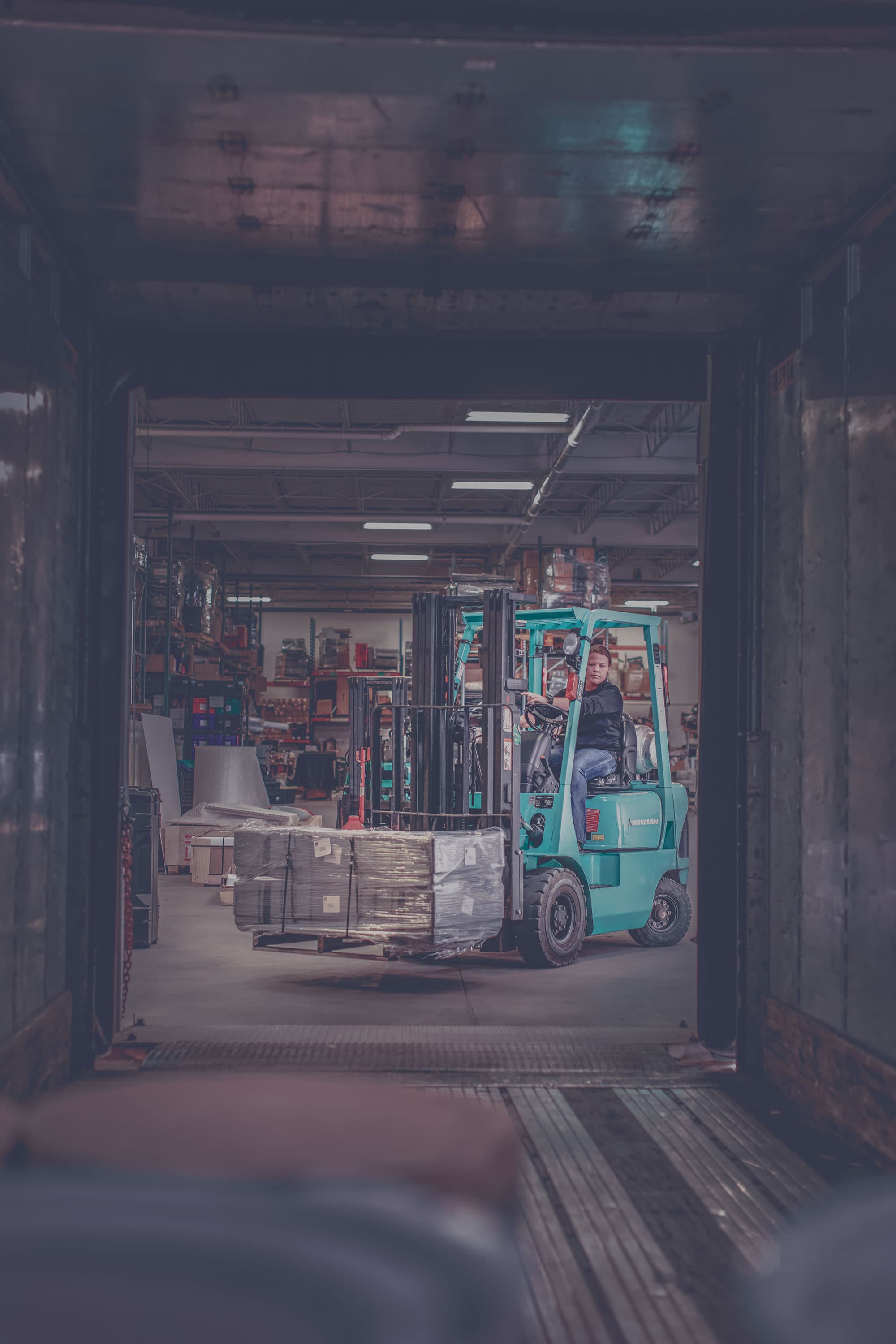 Propane-powered Forklift moving a skid into a shipping container. 