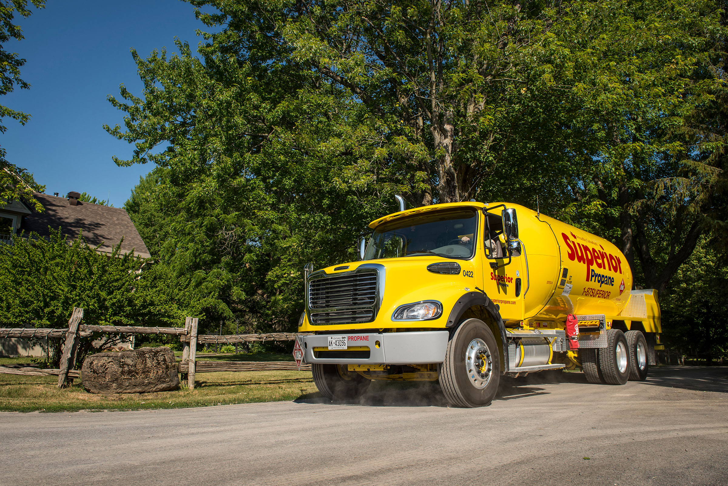 Superior Propane truck driving on a dirt road in a rural residential neighbourhood. 