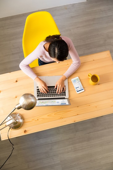 Woman sitting at a desk looking at mySUPERIOR on her laptop and mobile device. 