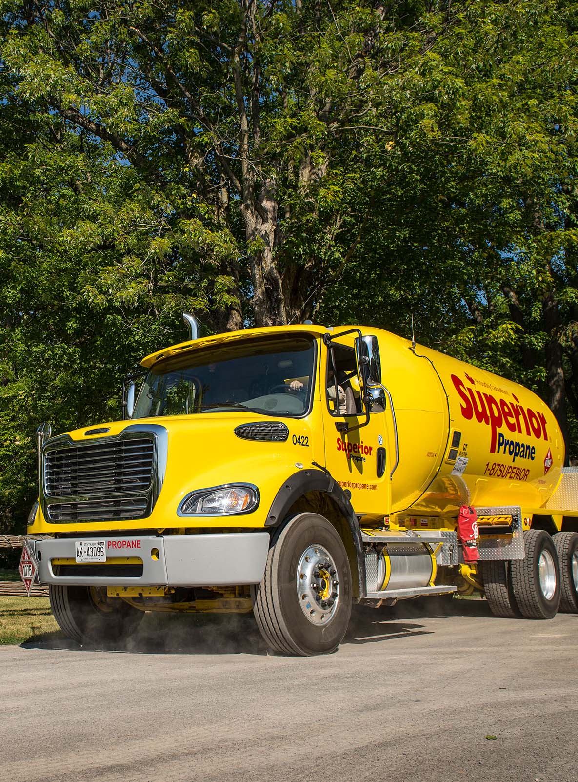 Superior Propane truck driving on a dirt road in a rural residential neighbourhood. 