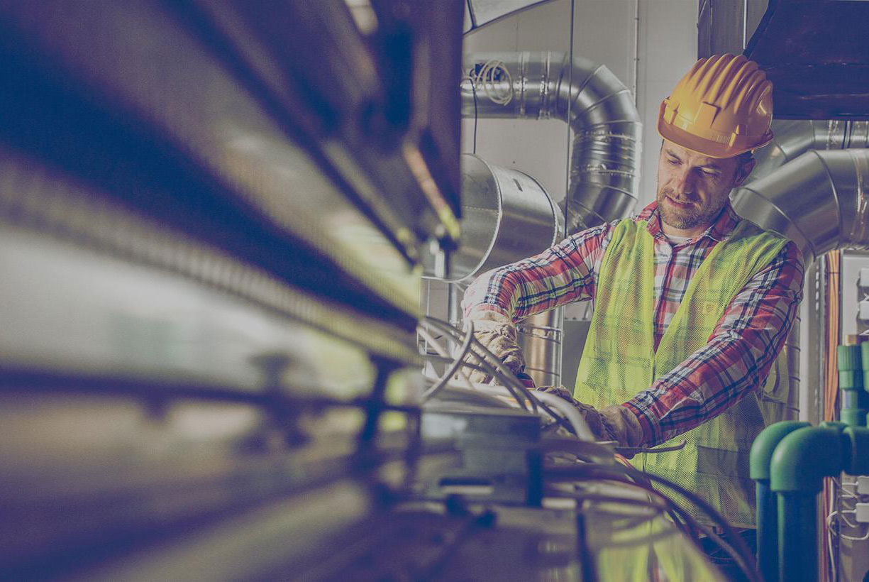 HVAC specialist working on the heating system in an industrial furnace room. 