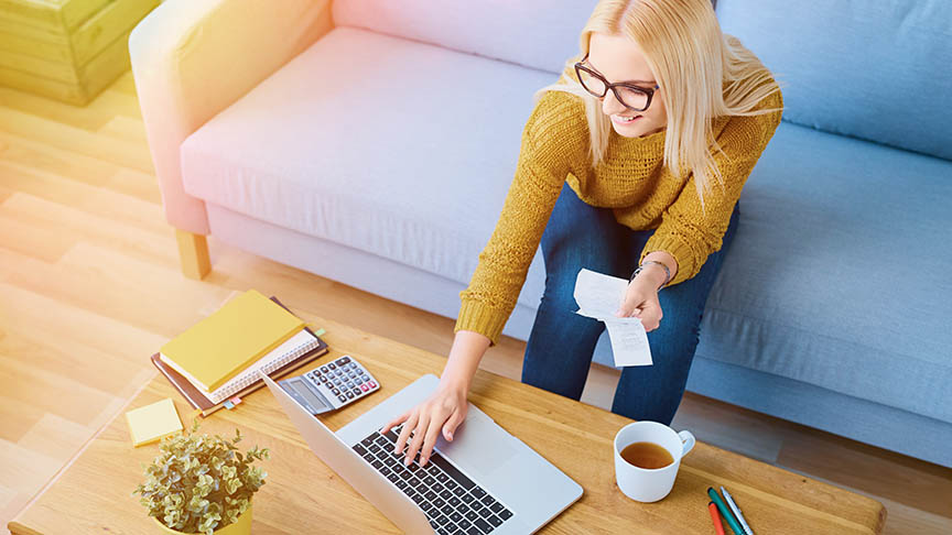 Woman paying her propane bill on her laptop via mySuperior while sitting on a couch.