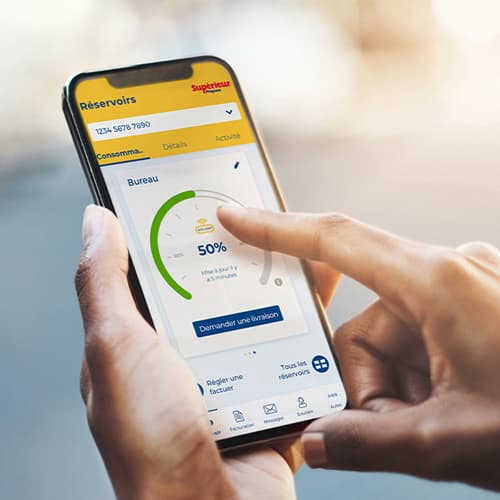 Femme, cellulaire à la main, lisant la jauge de niveau de propane de son réservoir à l'aide de l'application monSUPÉRIEUR.