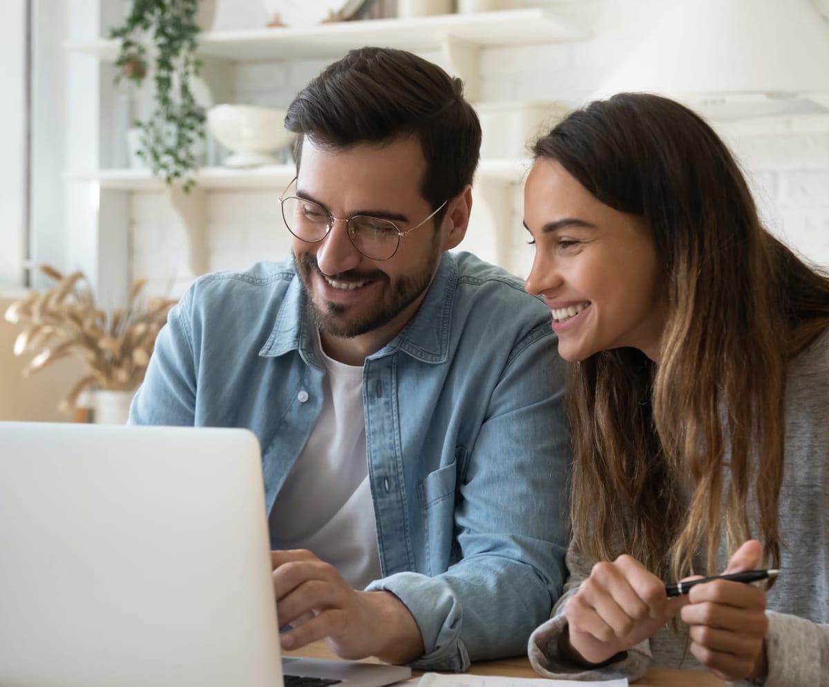 Happy young couple using a laptop to plan monthly budget