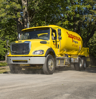 A yellow Superior Propane truck moving on a dirt road