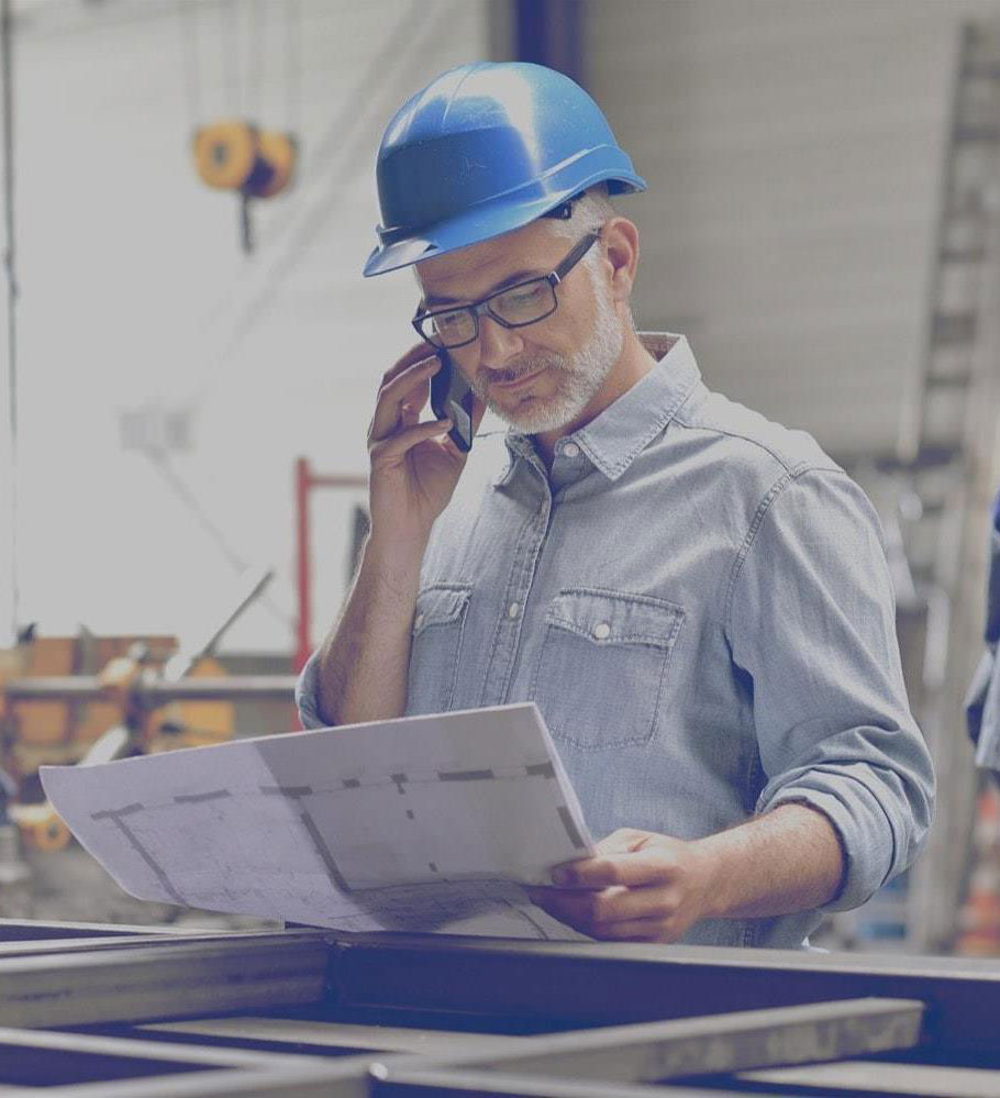 Safety inspector at a propane powered construction site looking at a blueprint and talking on a cell phone. 
