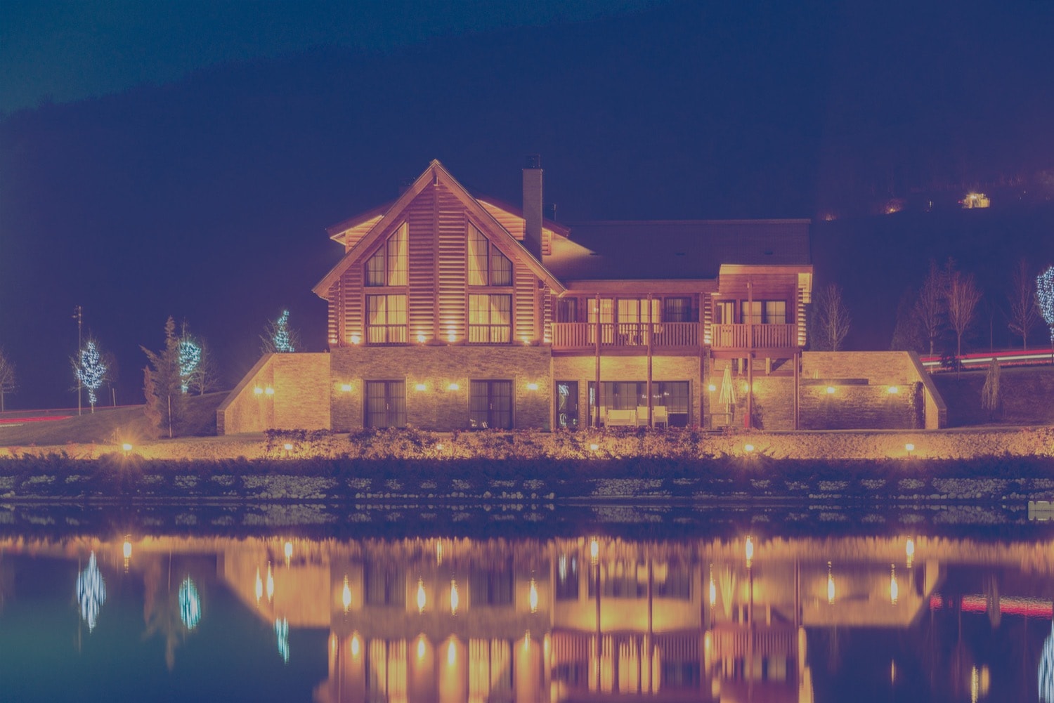 Large bed and breakfast home on a lake at night. 