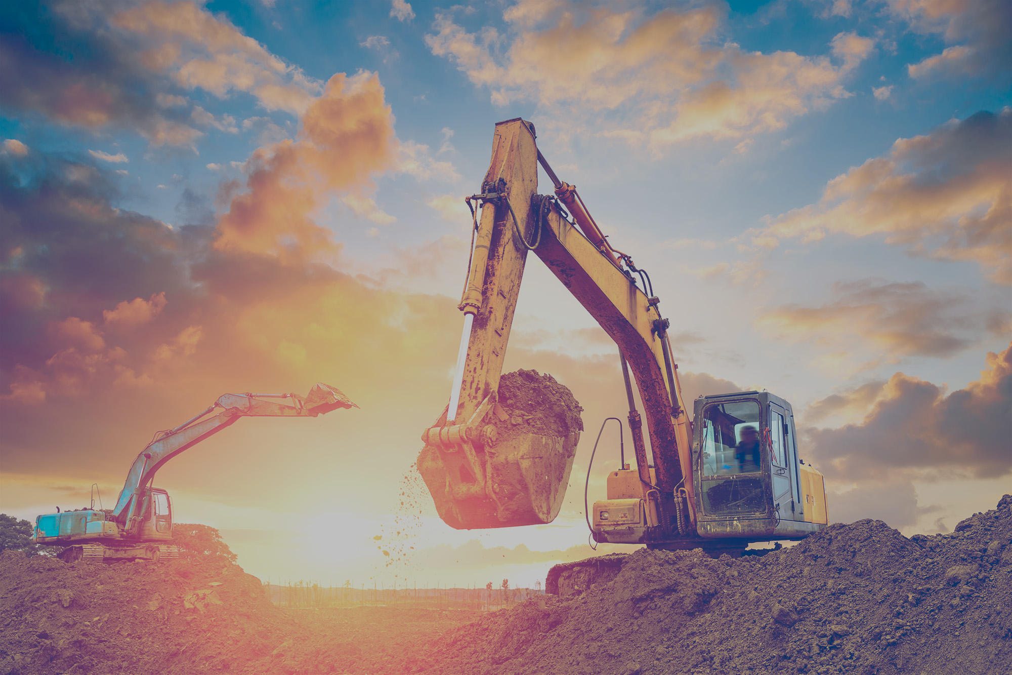 Two excavators digging in a pit of dirt on a construction site that is powered by propane. 