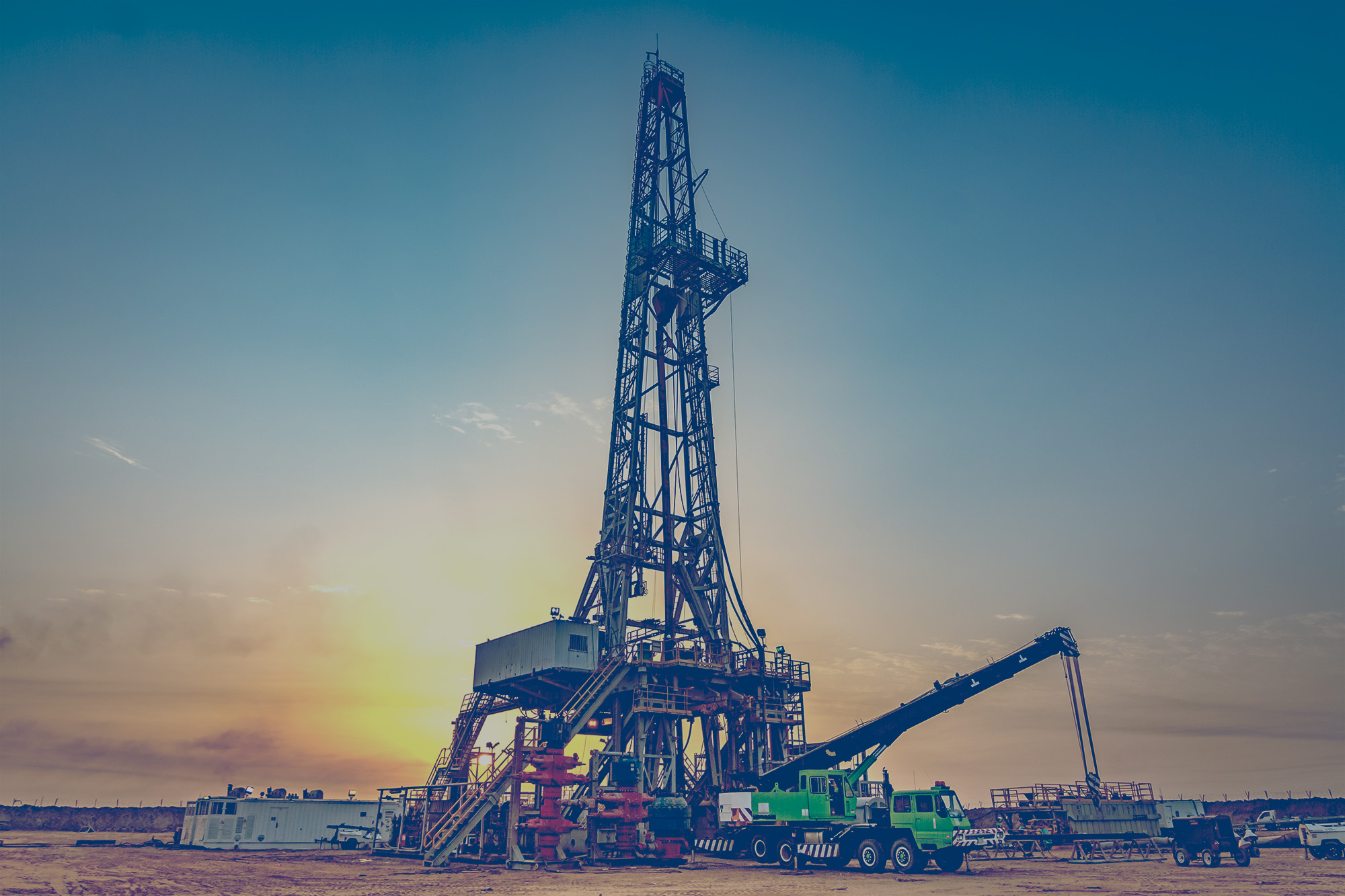 Large green fracking rig that is powered by propane with trucks and people working around it. 