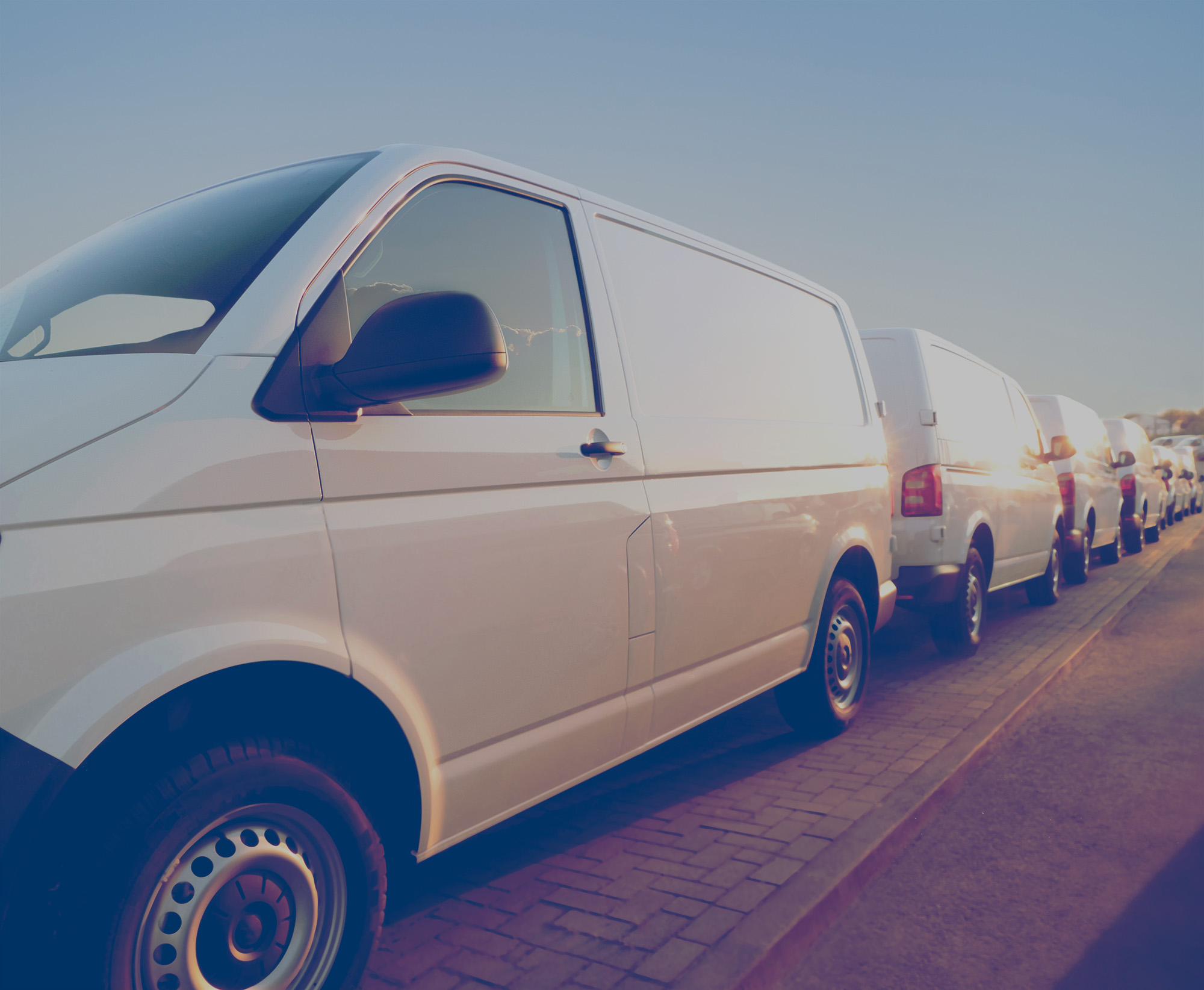 Fleet of white vans parked next to each other. 