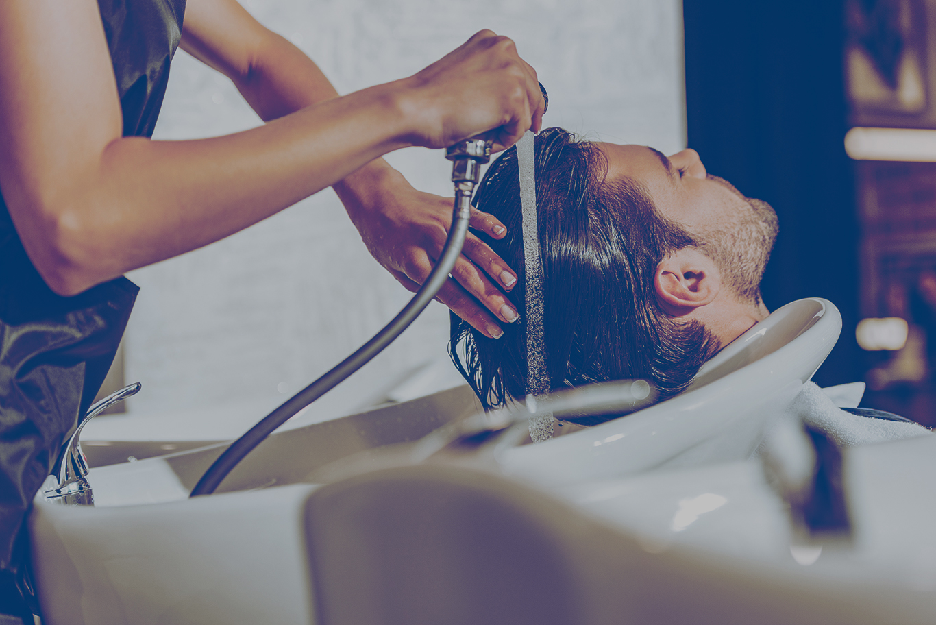 Hairdresser washing client’s hair in salon