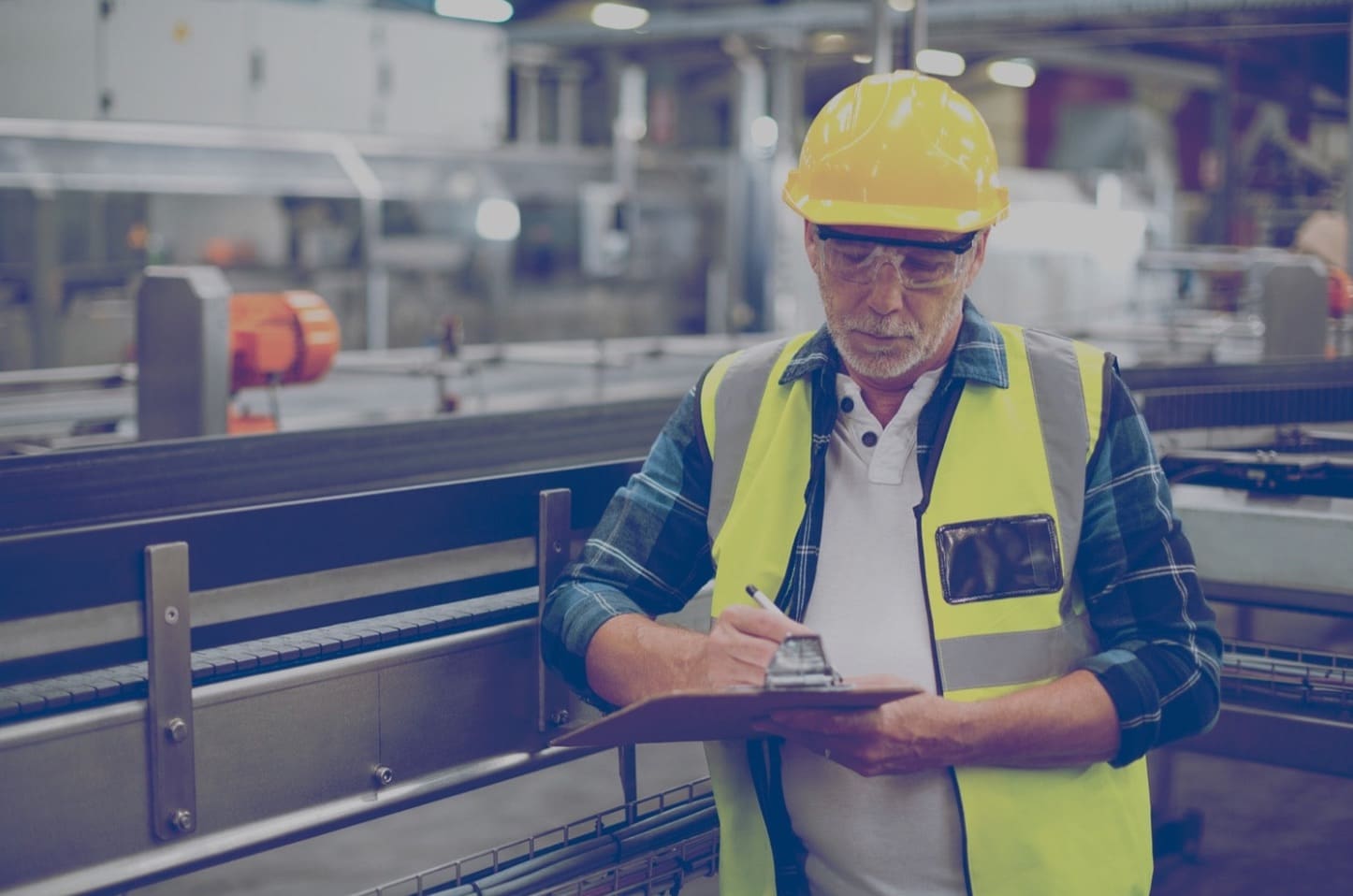 A construction worker inspecting the work area and writing on a clipboard.