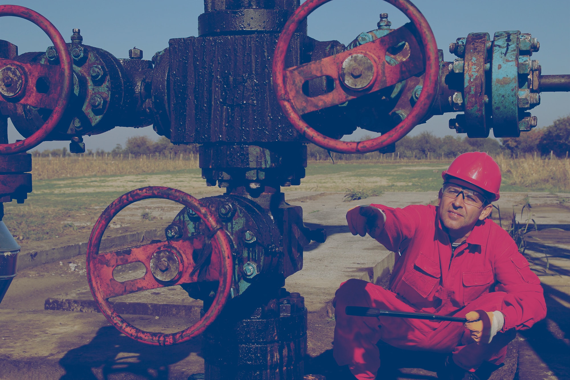 Worker inspecting pipes at an oil drilling site. 