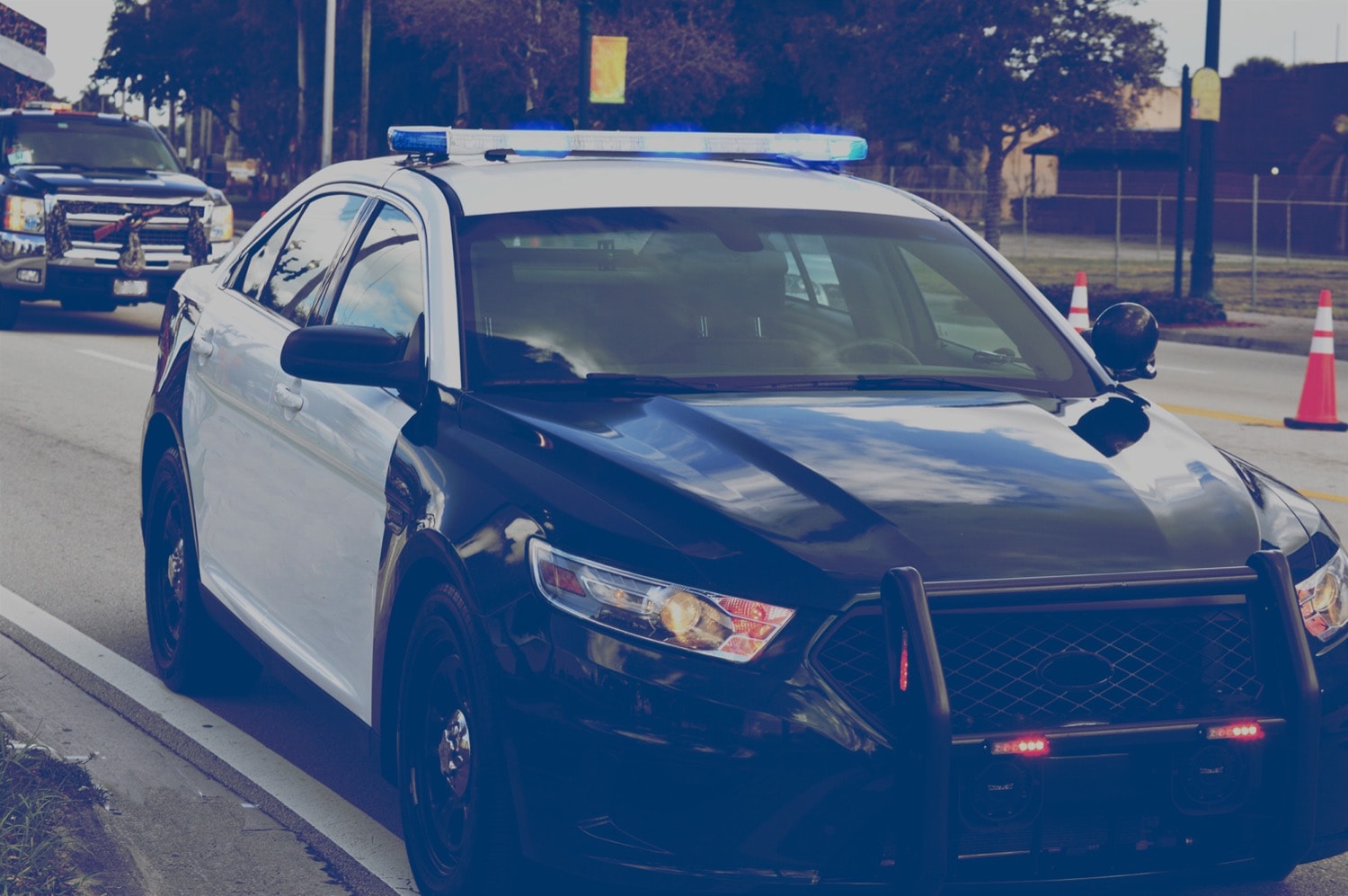 Police car parked at the side of the road with its sirens flashing. 