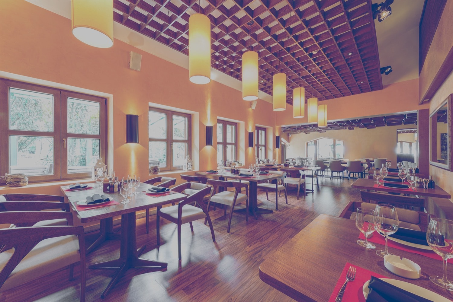 The interior of a modern restaurant. It is empty and the tables are set.