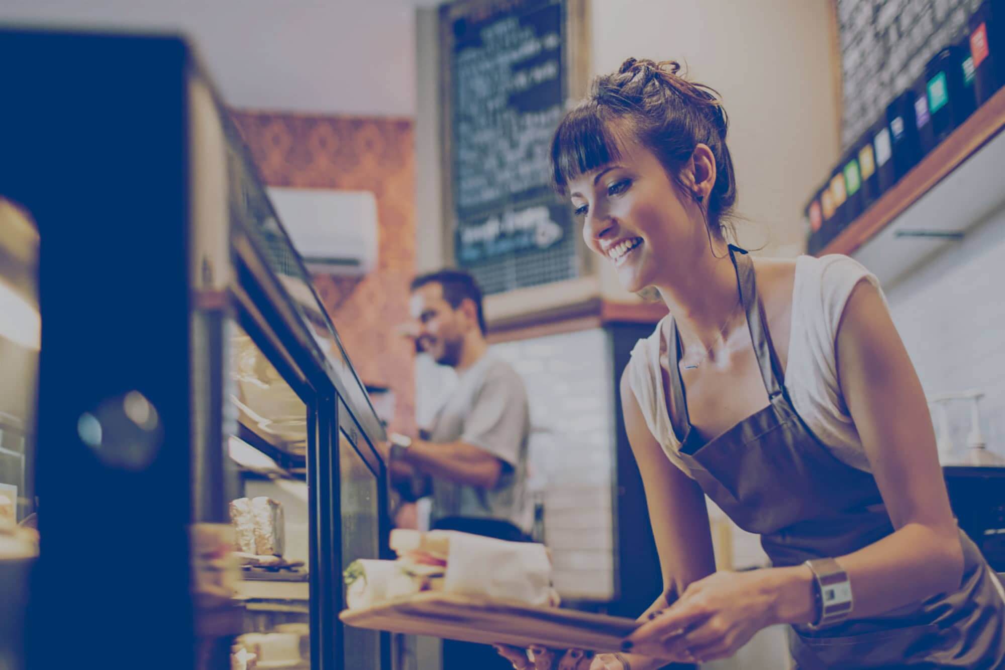 Restaurant employee grabbing a sandwich out of a showcase fridge. Click to learn how your business can save with propane. 