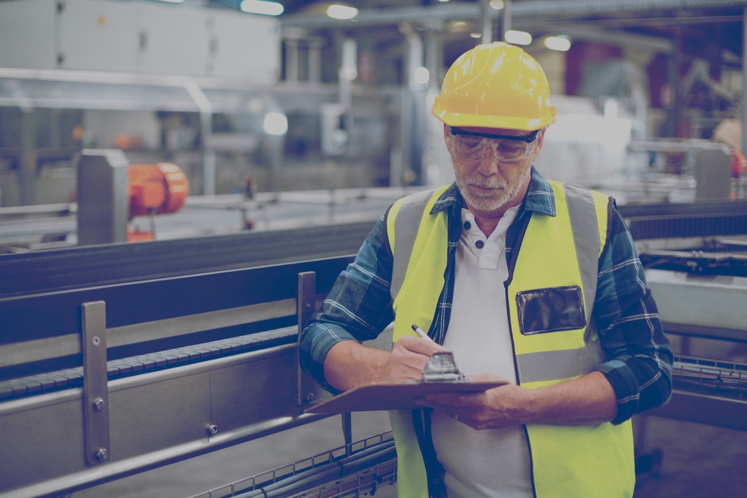 A safety inspector in an industrial plant looking at a clipboard. 