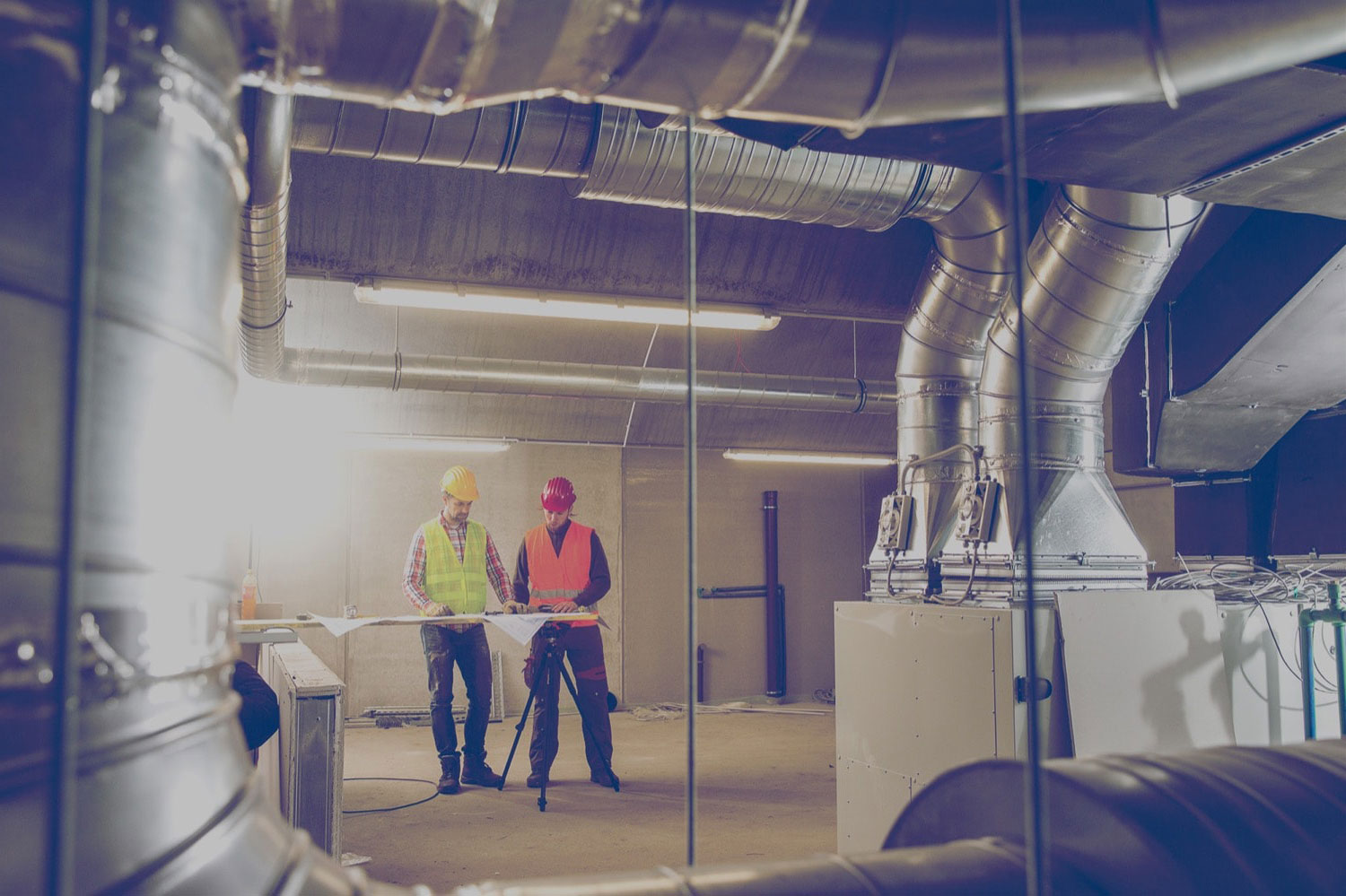 Workers looking at blueprints in an industrial propane furnace room.