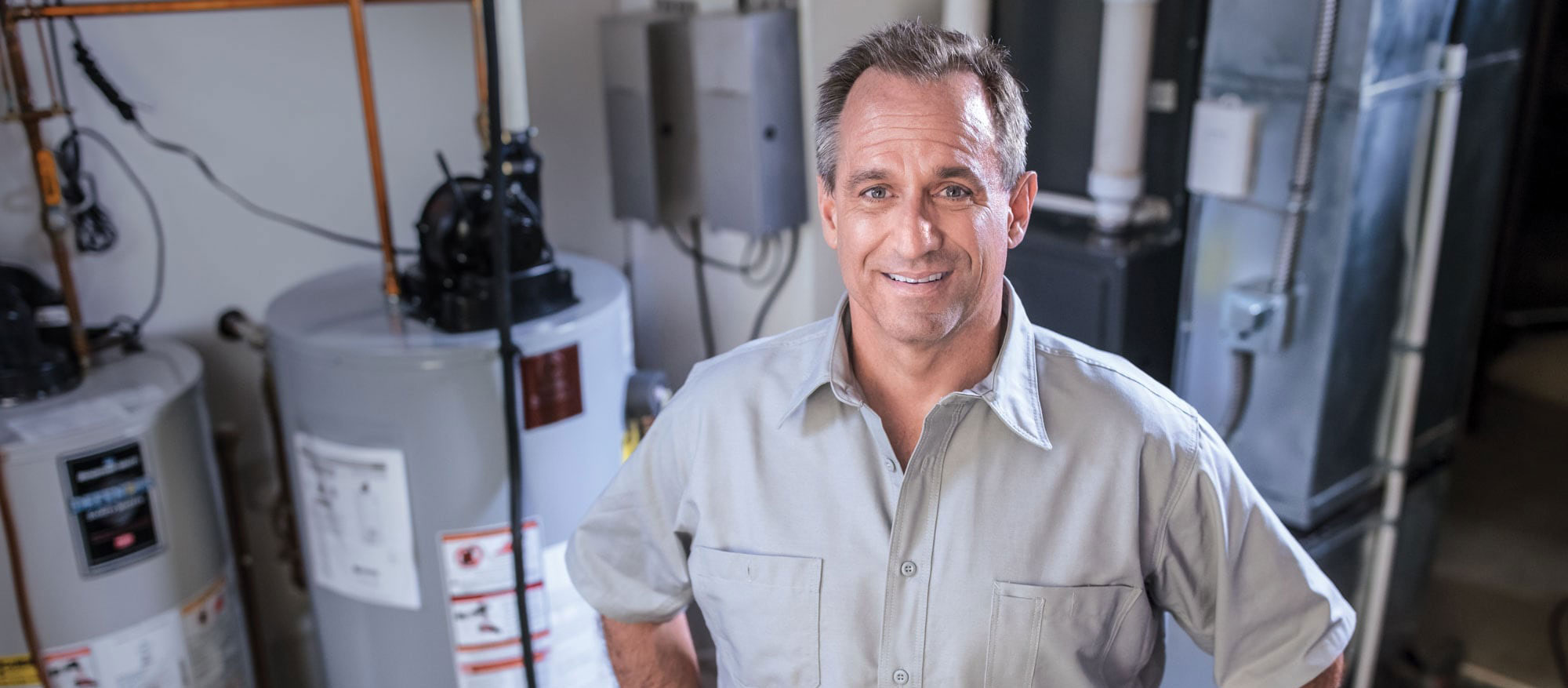 A Superior Propane partner technician standing in front of a furnace and water heaters. 