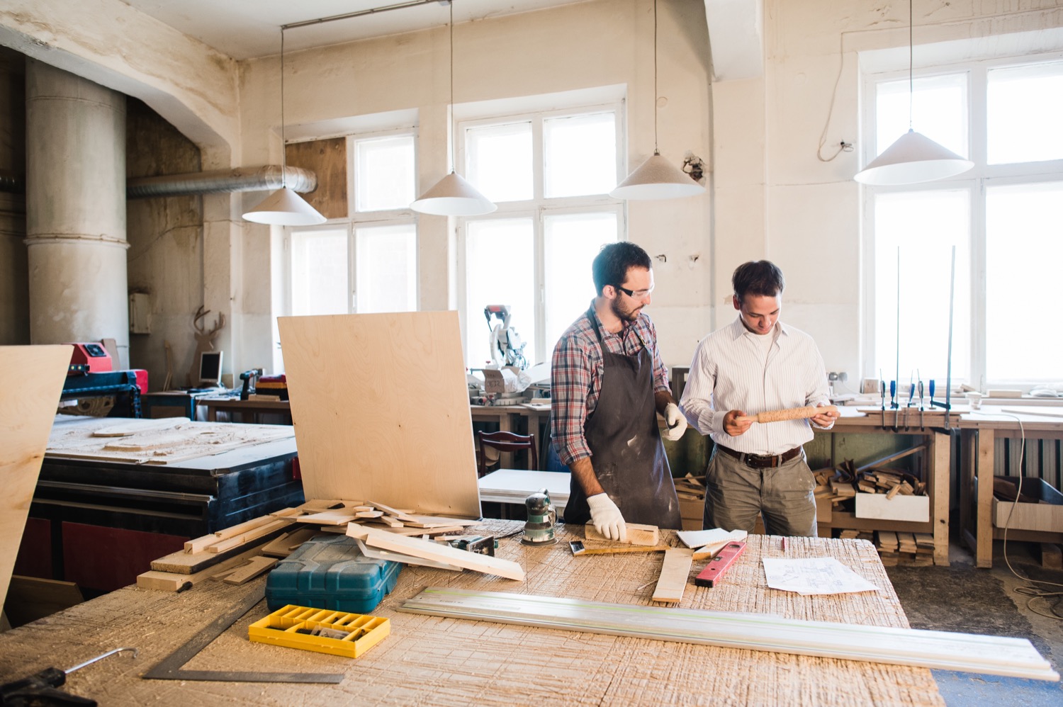 Two employees working in a small carpentry shop. 