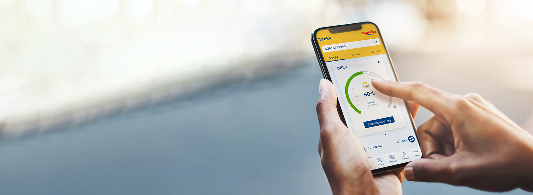 Woman holding cellphone, reviewing the amount of propane in her tank using the mySUPERIOR app. 