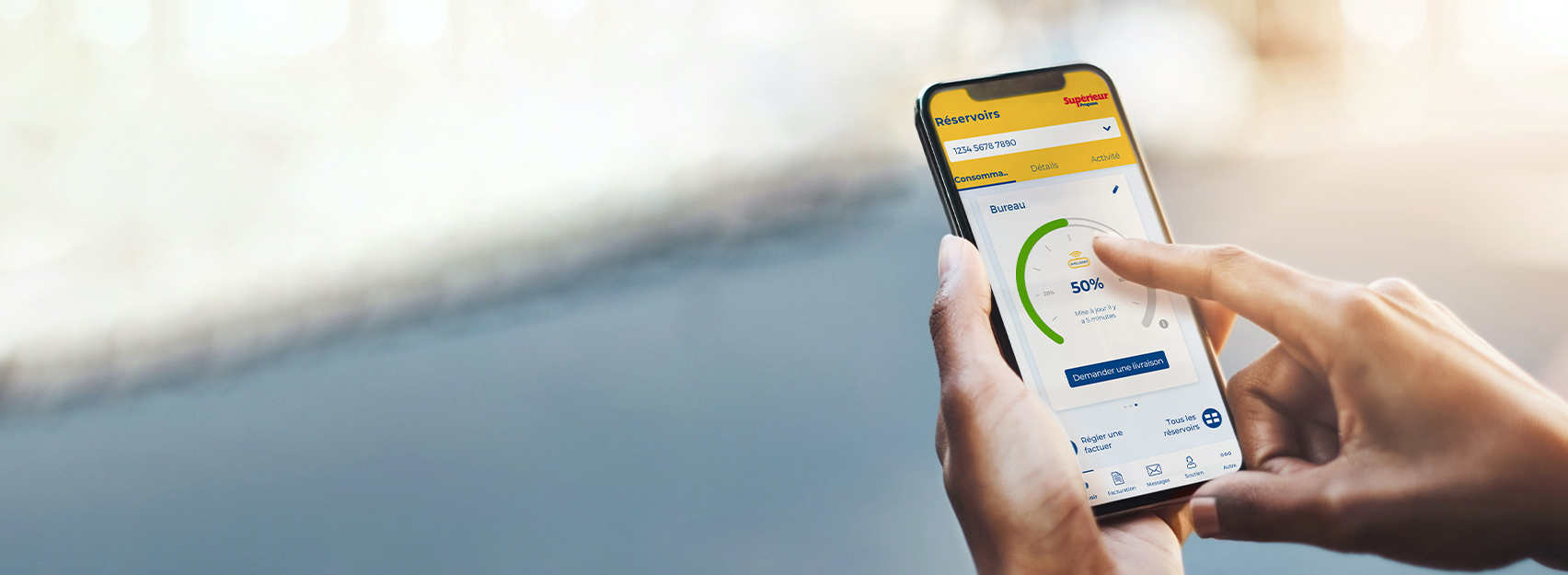 Une femme tient un cellulaire. Elle consulte la quantité de propane dans son réservoir grâce à l’application monSUPÉRIEUR.