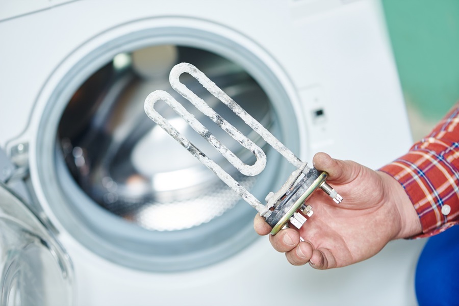 Plumber holding a water heating element that is covered in calcium. 