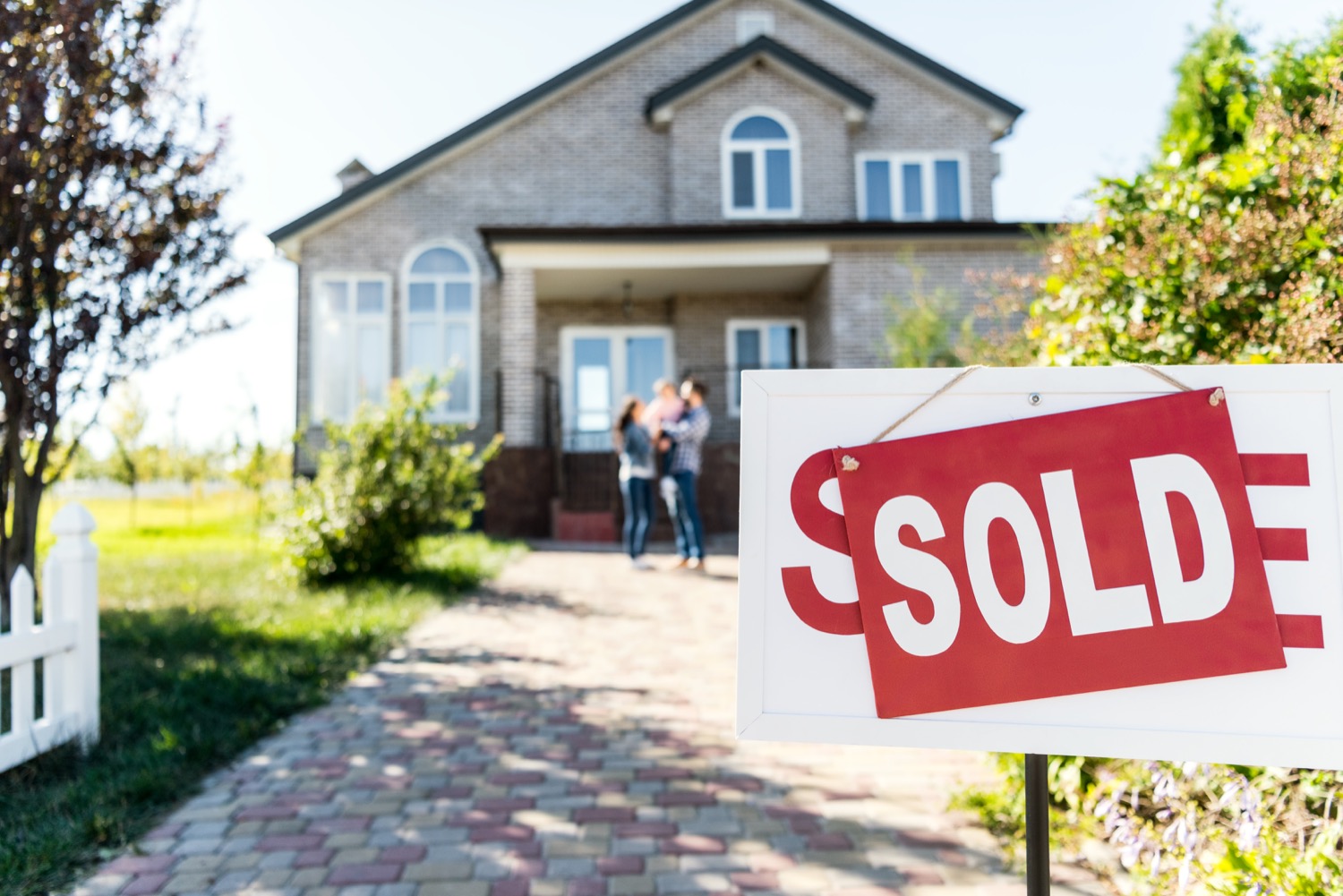 Sold sign and family with a small child in front of a new home that is heated by Superior Propane. 