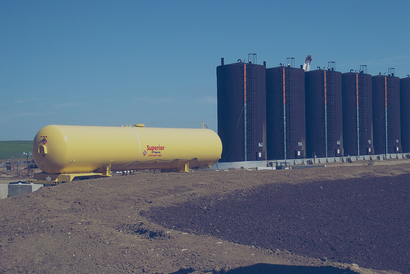 A large yellow Superior Propane tank next to several silos.