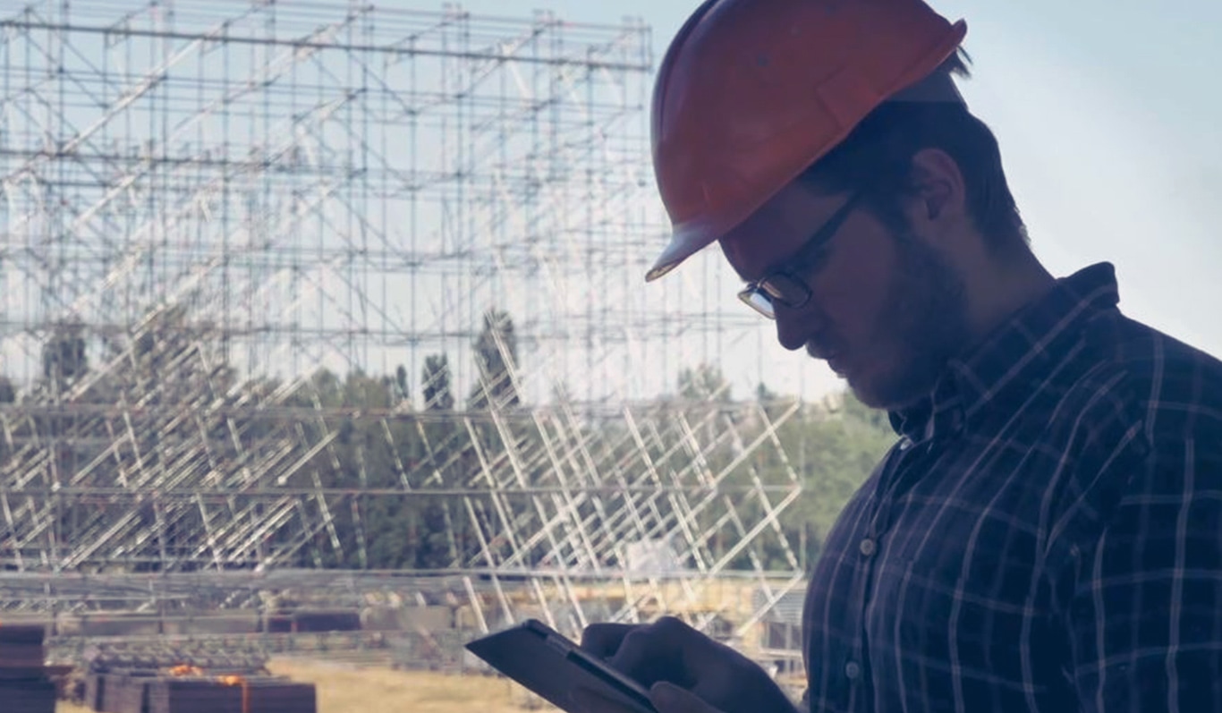 A construction worker on a job site looking at a tablet.