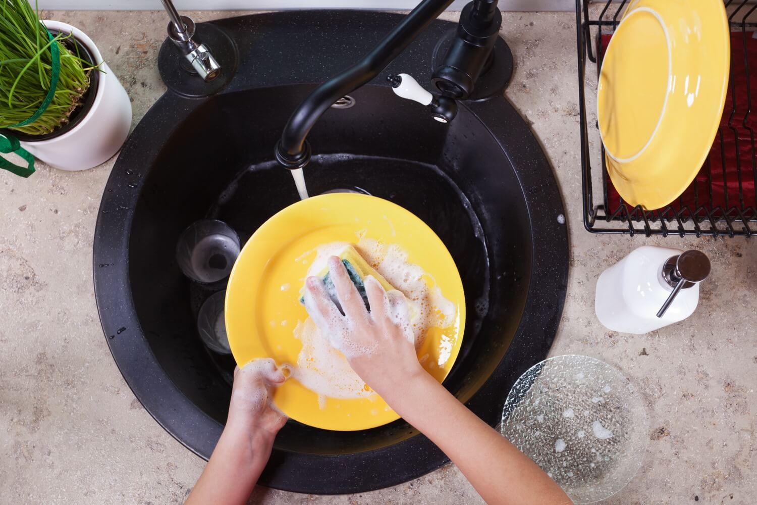Overhead view of a person washing a plate in the sink.