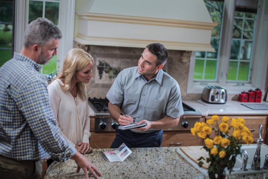 Superior Propane employee having a conversation with a couple in a kitchen. 