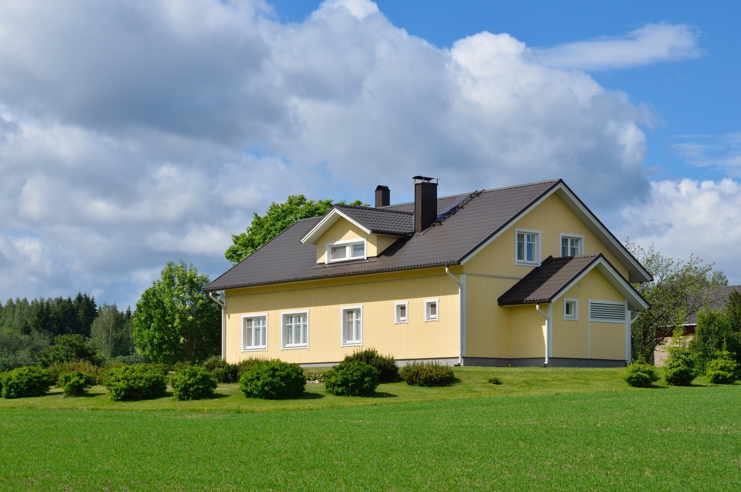 Yellow house in a green field in a rural area. 