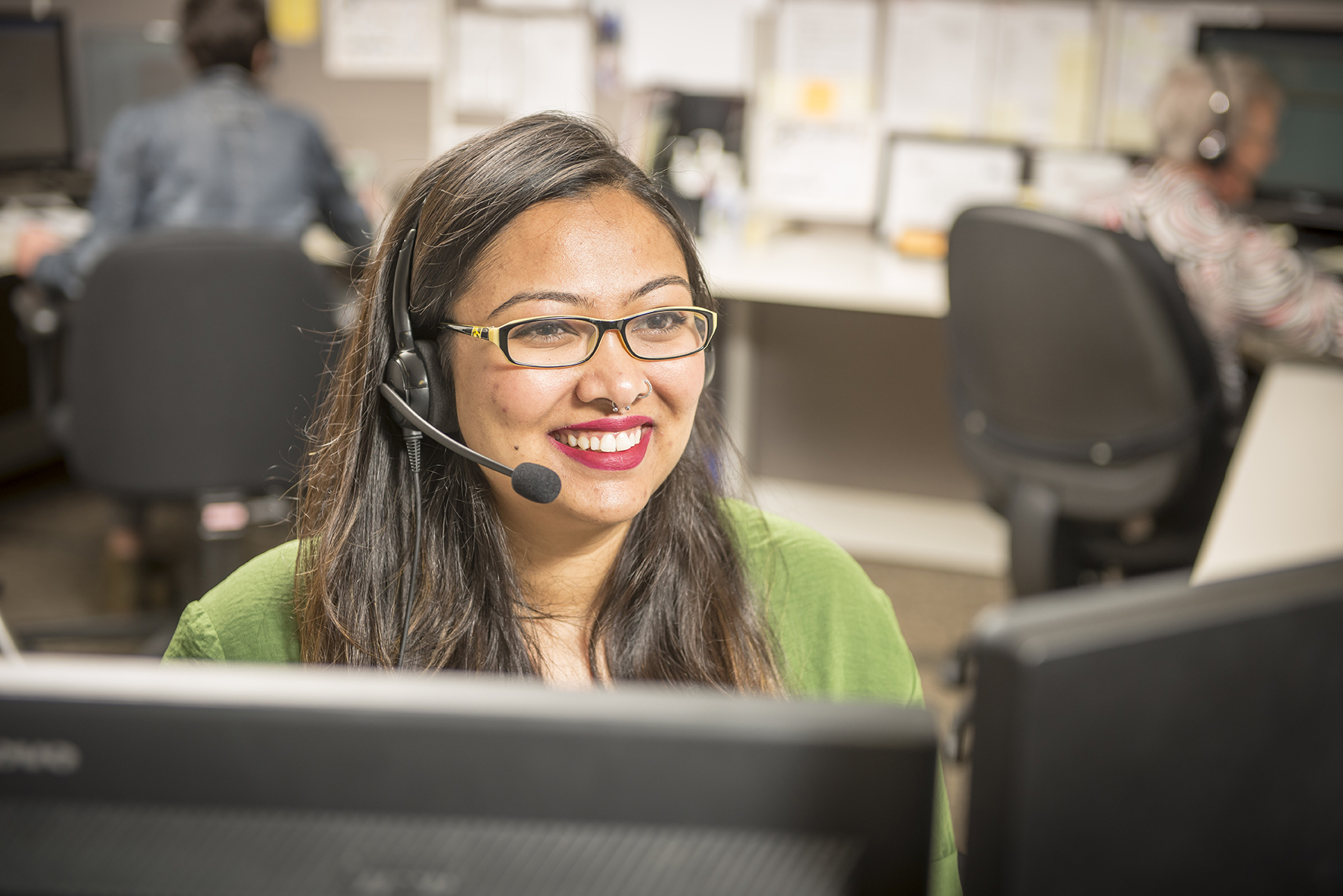 Souriant représentant du support client avec casque mains libres travaillant au bureau